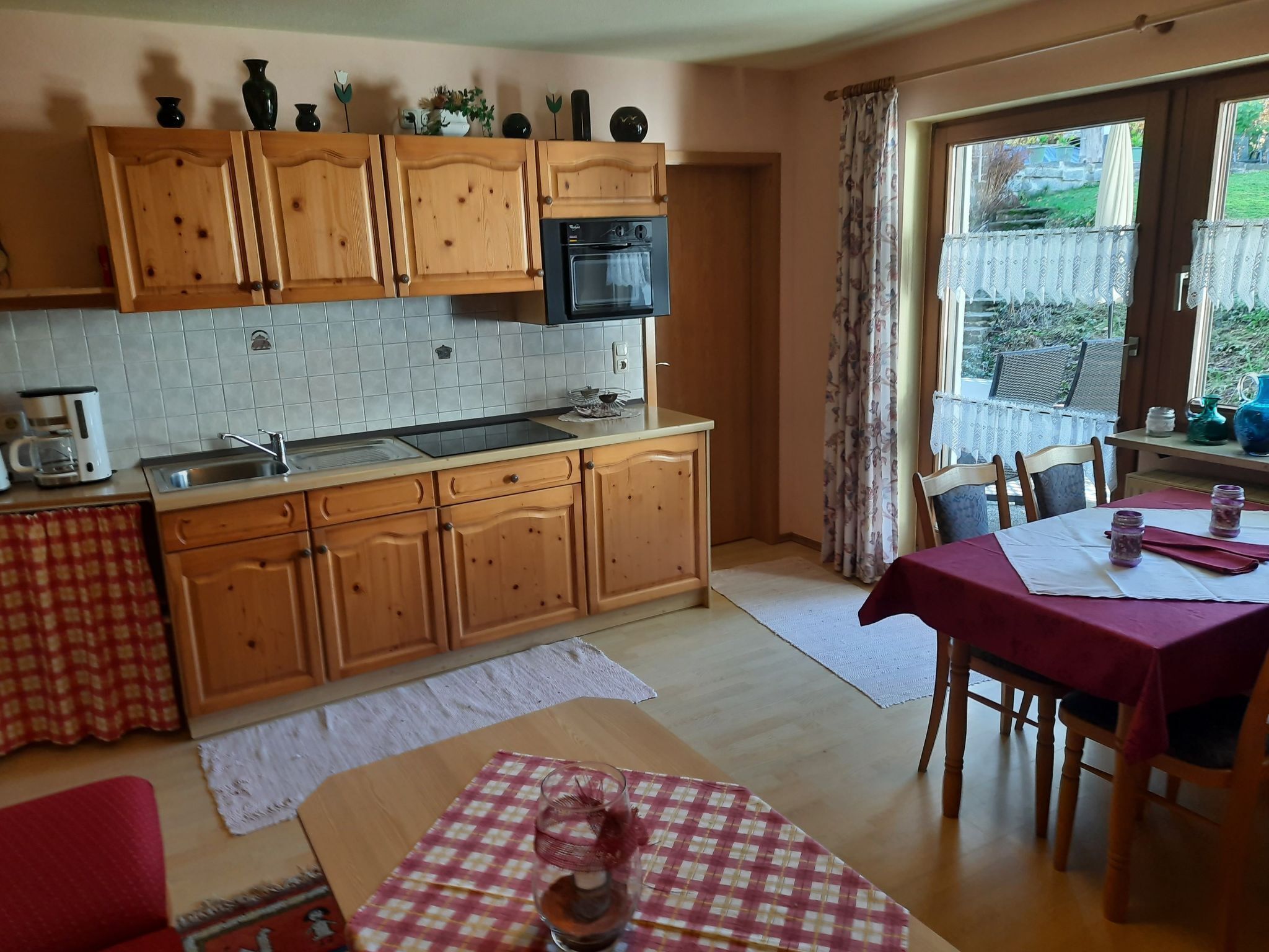 Eine Küche mit Holzausstattung, einem eingebauten Backofen und einem Essbereich mit Tisch für zwei Personen.