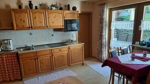 A kitchen with wooden cabinets, a built-in oven, and a dining area with a table set for two. - Seitz 2 in Bayerisch Eisenstein by Interhome (Bayerisch Eisenstein)