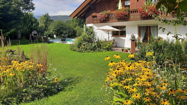 A wooden house with a balcony, a swimming pool, and a well-maintained garden with yellow flowers. - Seitz 2 in Bayerisch Eisenstein by Interhome (Bayerisch Eisenstein)