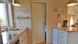 Eine moderne Küche mit Holzschränken, einem Einbauofen, einem Spülbecken und einer Kaffeemaschine.