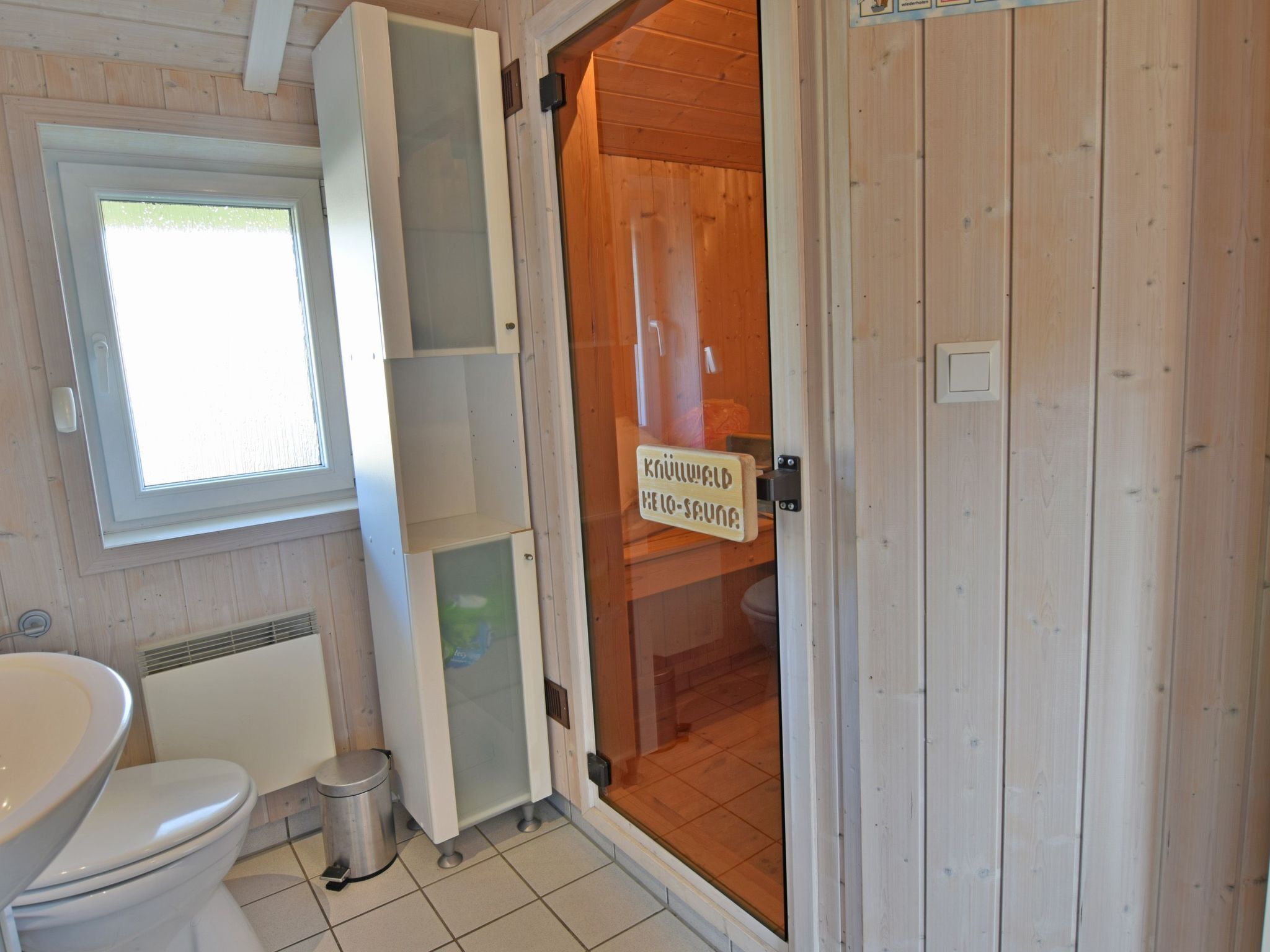 Een houten badkamer in een chalet, met toilet, wastafel en een douchecabine van glas.