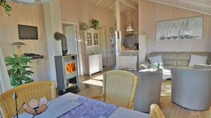Ein gemütliches Wohnzimmer mit Kamin, Korbmöbeln und einem Gemälde von Segelbooten.