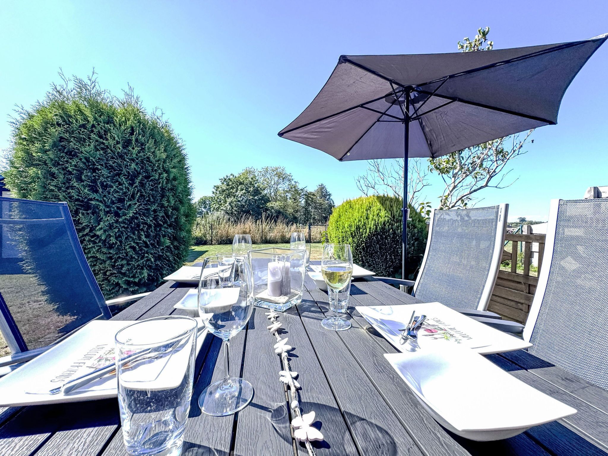 An outdoor dining area with a table set for two, complete with plates, glasses, and cutlery.