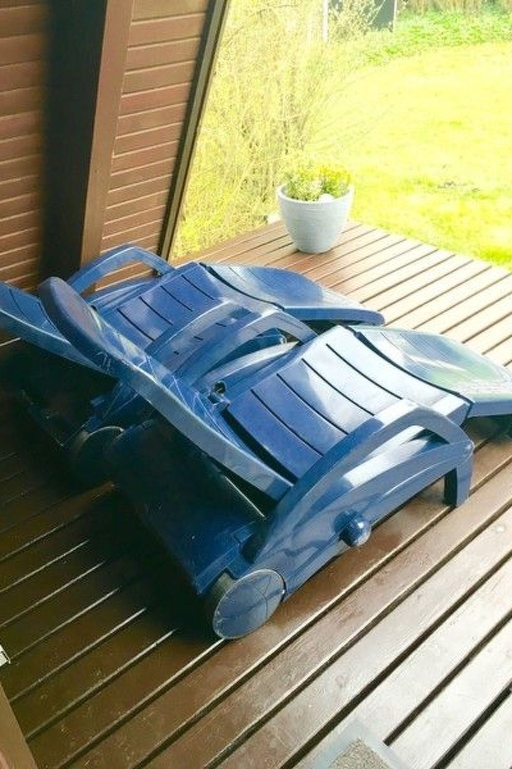 Two blue plastic lounge chairs on a wooden deck.