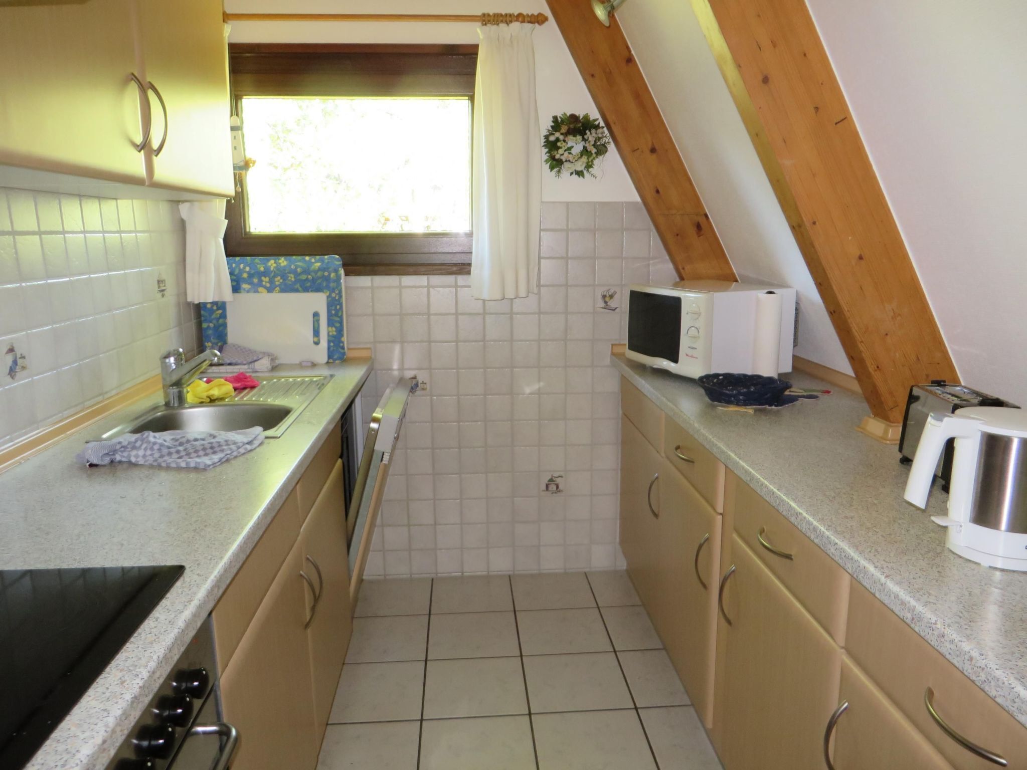 A compact kitchen with a stove, sink, and microwave.
