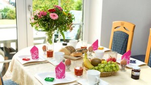 A breakfast table with a variety of foods, including bread, eggs, fruits, and a vase of flowers. - Uferpromenade 1 EG by Interhome (Waren)