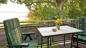 An outdoor seating area with a table and chairs, a potted plant, and a glass of wine. - Uferpromenade 1 EG by Interhome (Waren)