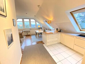 A modern kitchen with white cabinets, a dining area with a table and chairs, and large windows allowing natural light. - mit Stellplatz mitten im Grünen by Interhome (Kiel)