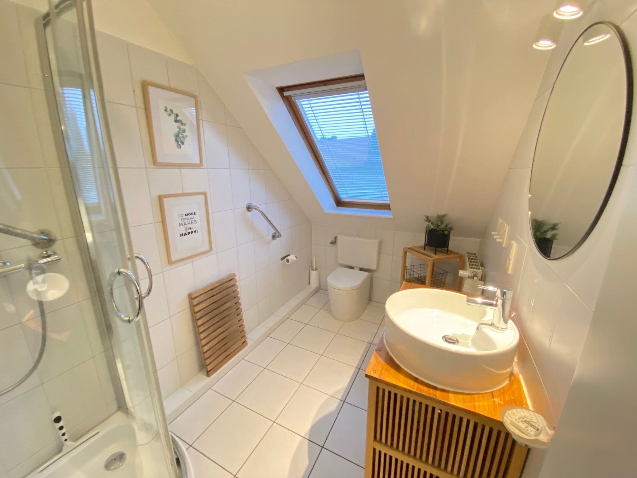 A modern bathroom with a glass shower enclosure, a skylight, a white sink, and a toilet.