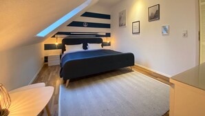 Une chambre à coucher avec un lit, des tables de chevet, un bureau et une chaise.
