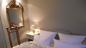 Quarto com cama, mesa de cabeceira, abajur, espelho e cômoda.
