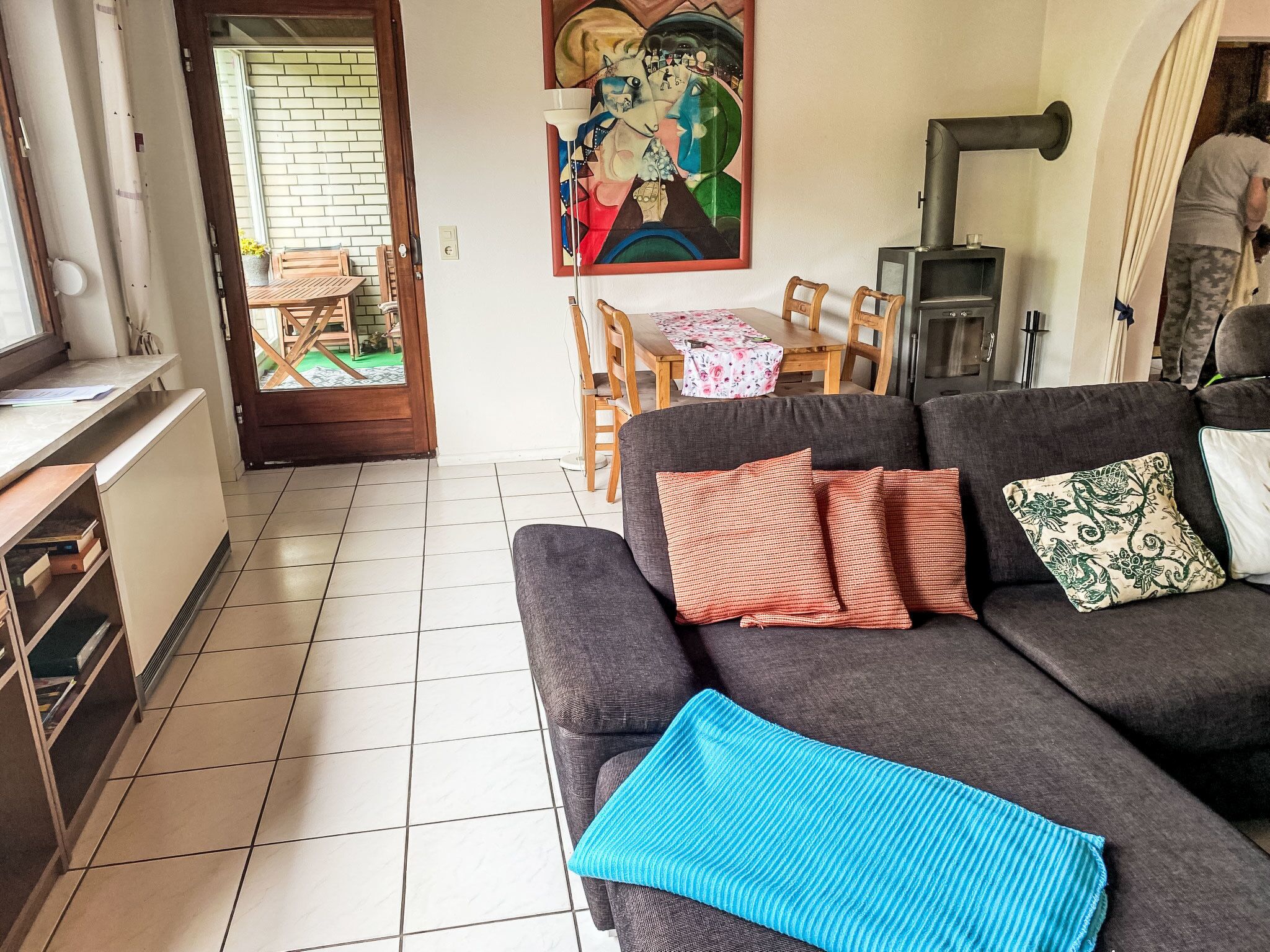 Ein Wohnzimmer mit einer Couch, einem Gemälde, einem Tisch mit Stühlen und einem Kamin.