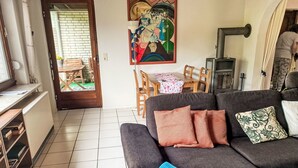 A living room with a sofa, a painting, a table with chairs, and a fireplace.