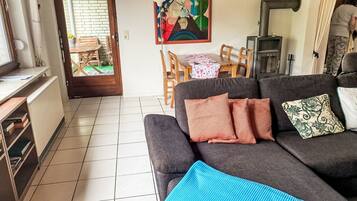 Ein Wohnzimmer mit einer Couch, einem Gemälde, einem Tisch mit Stühlen und einem Kamin.