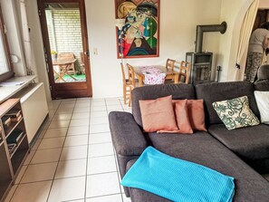 Ein Wohnzimmer mit einer Couch, einem Gemälde, einem Tisch mit Stühlen und einem Kamin.