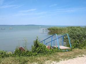 A lakeside view with a wooden dock and blue metal stairs leading into the water.