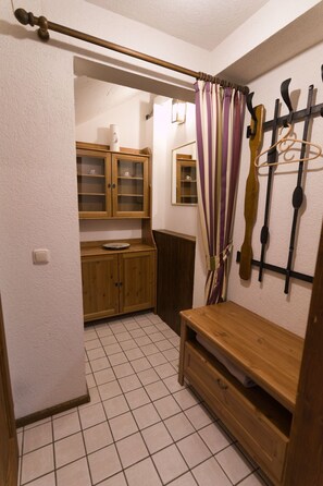 Ein kleines Badezimmer mit Fliesen, Holzschränken, einer Sitzbank und einer Duschvorhang.