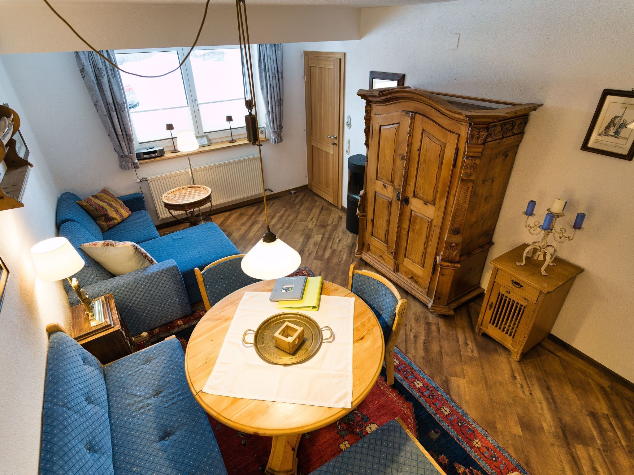 Una sala de estar acogedora con un conjunto de sofá azul, un aparador de madera y una mesa de comedor con un mantel individual.