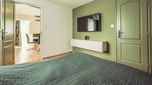 A bedroom with a bed, a TV mounted on the wall, a door, and a hallway leading to a dining area. - Caesar Apartment mit Terrasse, nahe dem Balaton by Interhome (Siofok)