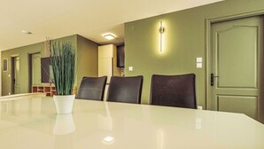 A conference room with a long table, four chairs, a potted plant, and a door with a light switch. - Caesar Apartment mit Terrasse, nahe dem Balaton by Interhome (Siofok)