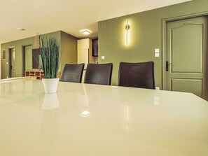 A conference room with a long table, four chairs, a potted plant, and a door with a light switch. - Caesar Apartment mit Terrasse, nahe dem Balaton by Interhome (Siofok)