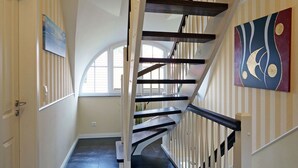 Eine Treppe mit weißen Geländern und dunklen Stufen, die zu einer oberen Etage führt.