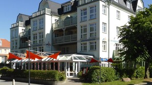 Ein mehrstöckiges Hotel mit Balkonen, einem überdachten Eingang und einem Schild, das es als Hotel kennzeichnet.