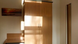 Ein Hotelzimmer mit großem Holzschrank, einem Bett, einer Bank und einem Gemälde an der Wand.