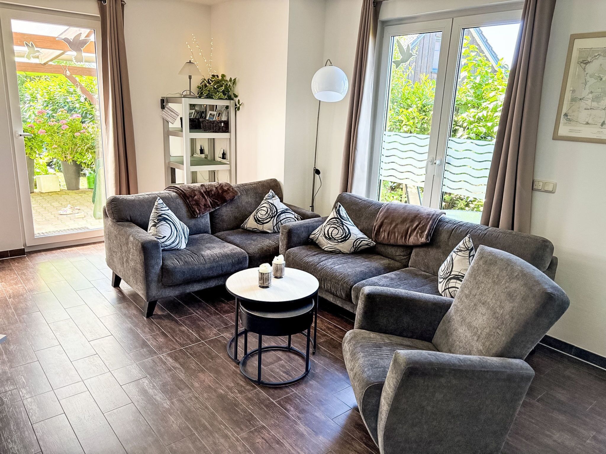 Sala de estar con un sofá gris, una mesa de centro redonda y un sillón.