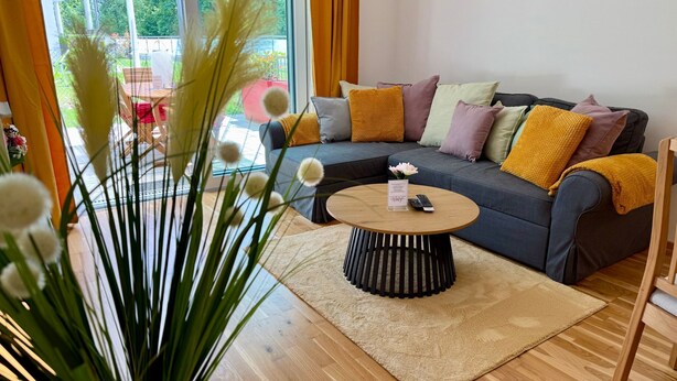 Ein modernes Wohnzimmer mit Sofa, Couchtisch und Blick ins Freie.