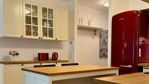 Eine moderne Küche mit weißen Schränken, einer Holzarbeitsplatte und einem roten Kühlschrank.