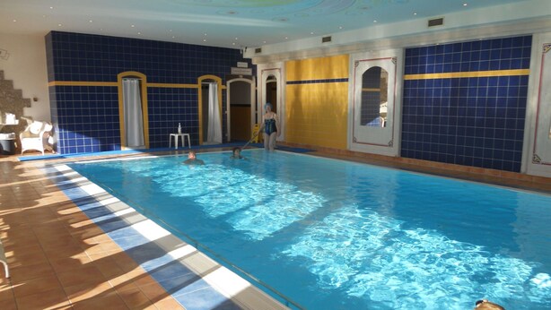 An indoor swimming pool with clear blue water, tiled walls, and a tiled floor. - mit Gemeinschaftspool und Terrasse by Interhome (Bad Waltersdorf)