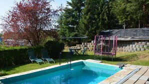 A rectangular swimming pool with a stone border, surrounded by a grassy area and trees. - kunstsammler by Interhome (Dresden)