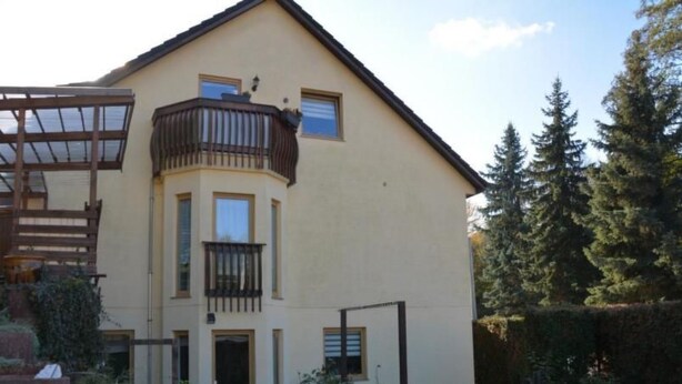 A two-story house with a balcony, a front door, and a small garden area. - kunstsammler by Interhome (Dresden)