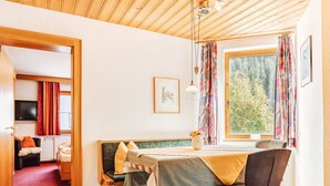 A cozy room with a wooden ceiling, a bed with a green headboard, a desk with a chair, and a window with curtains. - Sarah in Galtür by Interhome (Galtür)
