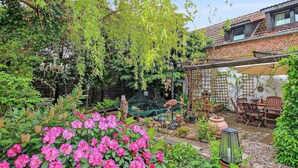 A garden with a brick house, a pergola, and outdoor furniture. - Appartement in Meiersberg mit Grill by Interhome (Altwarp)