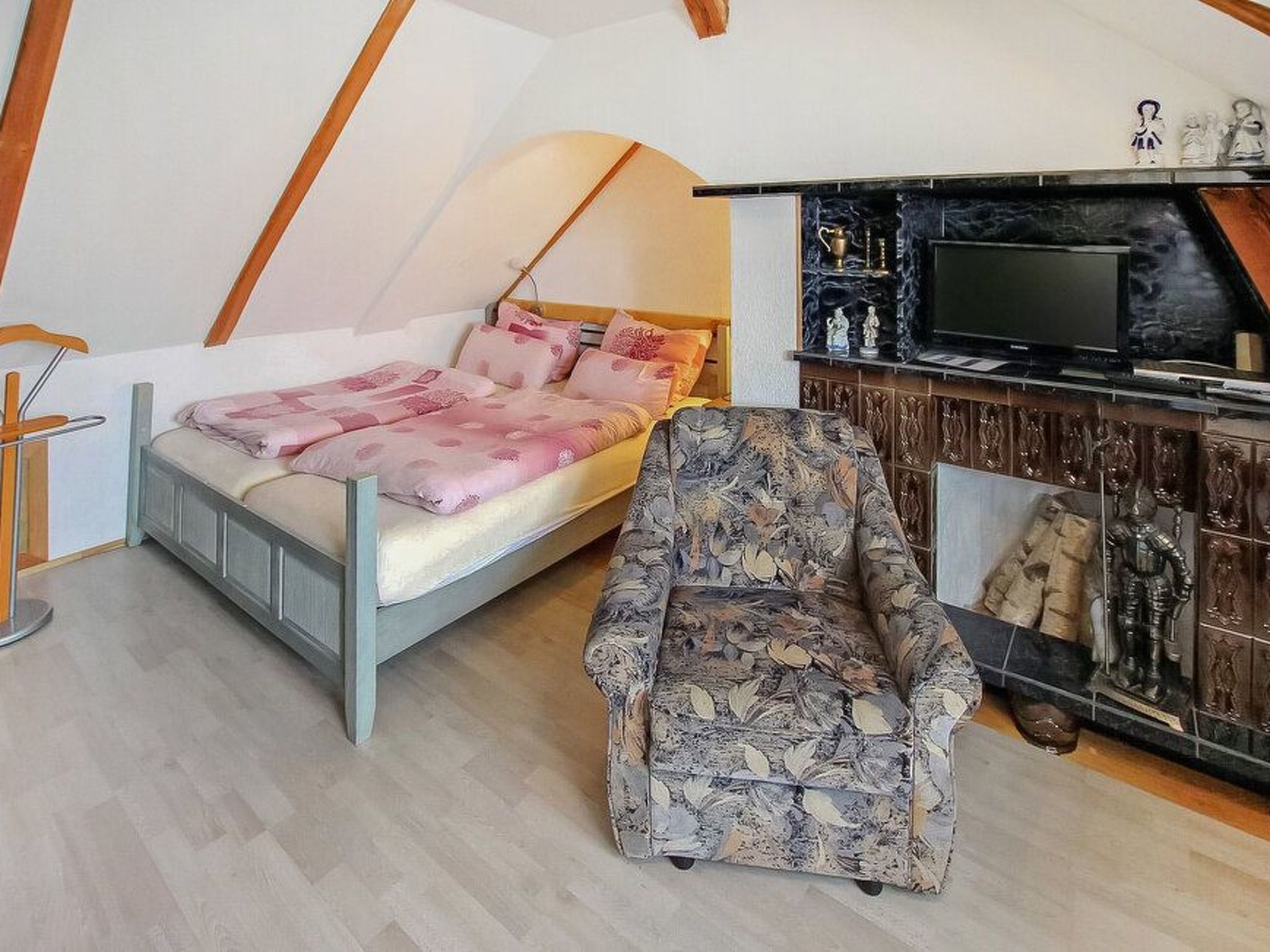 Une chambre à coucher comprenant un lit, une chaise, un téléviseur et une étagère avec des objets décoratifs.