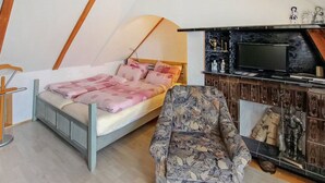 A bedroom with a bed, a chair, a TV, and a shelf with decorative items. - Appartement in Meiersberg mit Grill by Interhome (Altwarp)