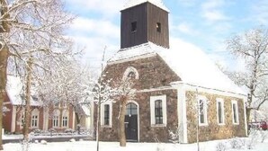 A stone church with a bell tower, surrounded by snow-covered trees. - Appartement in Meiersberg mit Grill by Interhome (Altwarp)