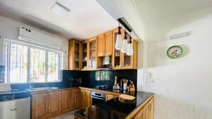 A kitchen with wooden cabinets, a black countertop island, and a window with blinds. - in Roches Noires mit Großem Garten by Interhome (Cap Malheureux)