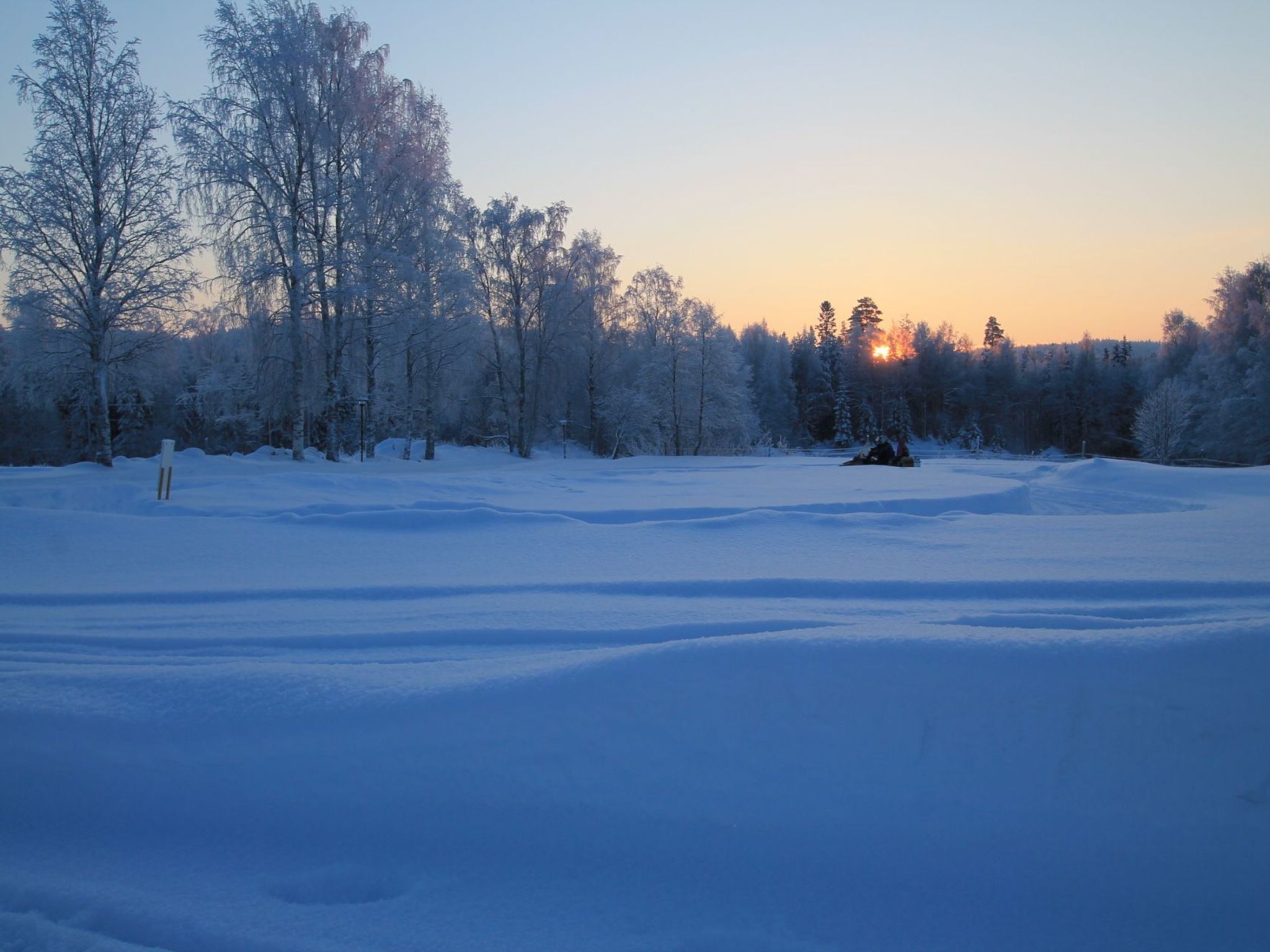 Un paysage enneigé, avec un ciel dégagé et un coucher de soleil.