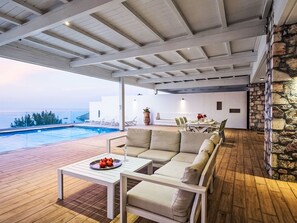 A modern outdoor patio with a pool, seating area, and a dining table. - Villa Kleovoulini by Interhome (Pefki)