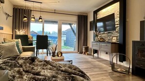 Un salon moderne avec un grand lit, une télévision et une cheminée.