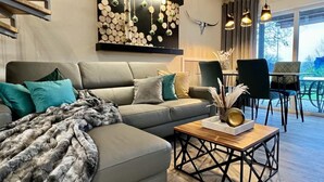 Un salon moderne avec un canapé gris, des coussins turquoise, une table basse en bois et un élément décoratif mural.