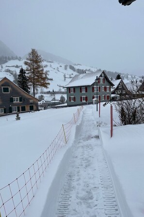 Un sentiero innevato che conduce a un edificio con tetto rosso e pareti bianche.