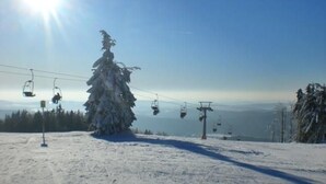 A snow-covered ski slope with a ski lift and a clear sky.