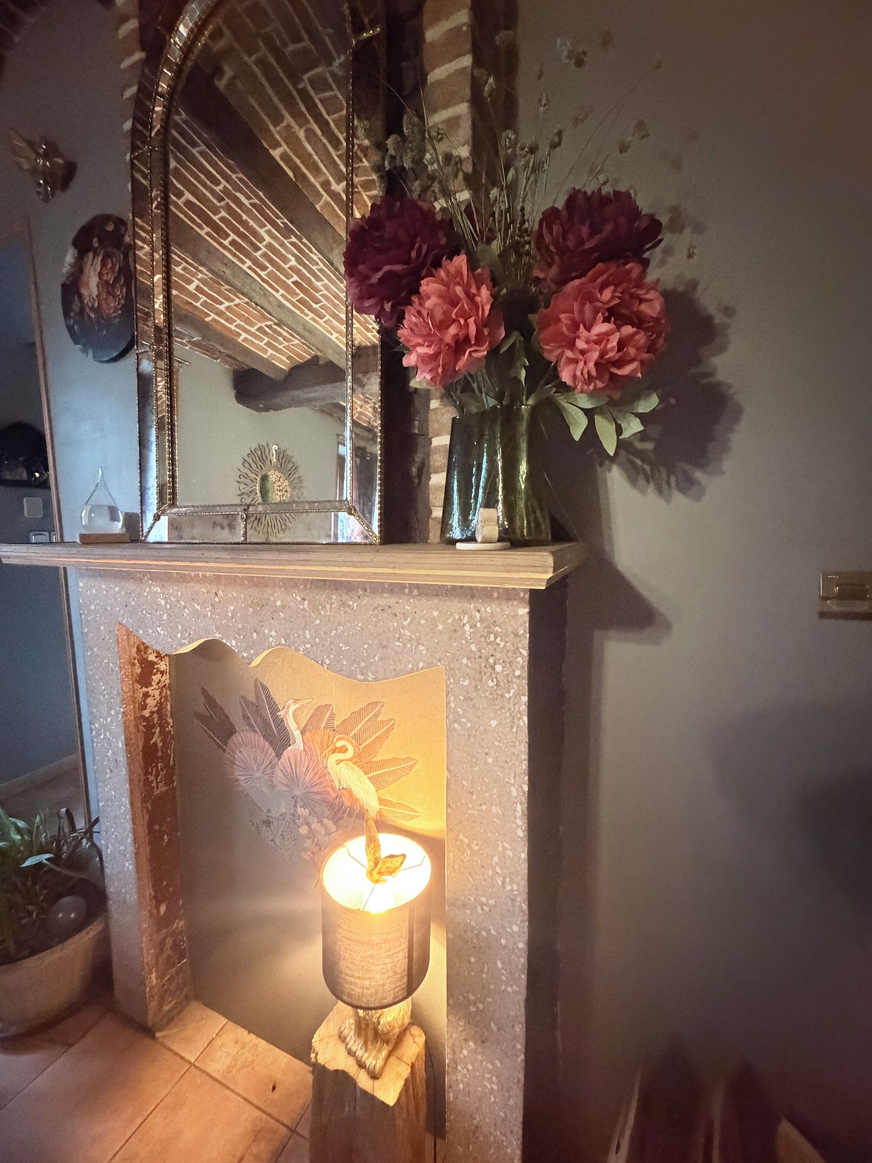 Ein Badezimmer mit Spiegel, Blumen in einer Vase und einer dekorativen Lampe.