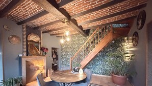 Un comedor con una mesa redonda de madera, dos sillas, un tapete estampado y una escalera con barandilla de madera.