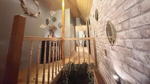 Una escalera de madera con barandilla que lleva a un cuarto con pared de ladrillo y espejos decorativos.