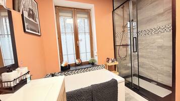 Un baño moderno con bañera, cabina de ducha de vidrio y ventana con vidrio esmerilado.